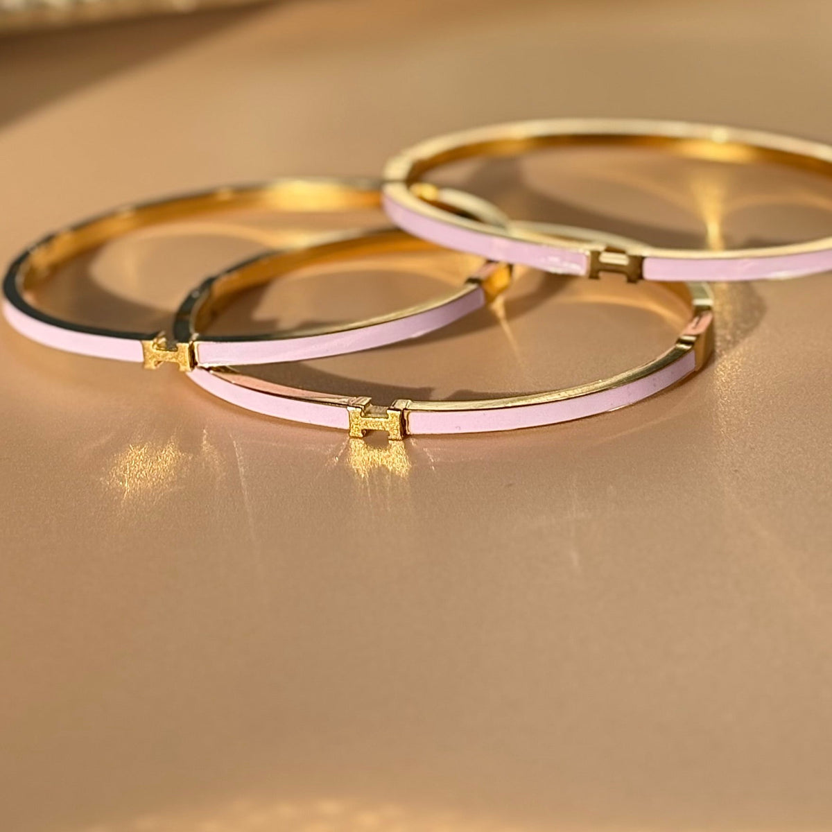 Two gold bracelets with pink interior on a gold background
